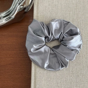 Detailed view of dark silver satin scrunchie on grey fabric book cover in elegant setting