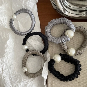 Detail of satin scrunchies with white faux pearls in neutral tones on minimal background