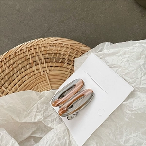 Détail de deux barrettes ovales en acétate marron sur un panier tressé élégant