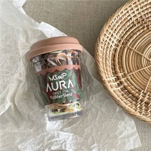 Detail of colorful high elasticity hair ties inside a clear cup with floral packaging