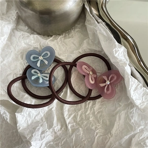 Détail de quatre élastiques à cheveux cœurs colorés avec nœuds 3D, strass et motifs faits main