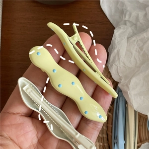 Close-up of cream-colored wave dot hair clips held by hand for size reference
