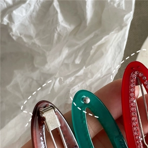 Detailed close-up of acetate hair clips with inlaid rhinestones in brown, green and red