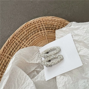 Gros plan de barrettes en acétate à motif marbré sur un plateau en osier tissé