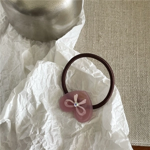 Détail de l'élastique à cheveux cœur rose avec gravure et petit nœud blanc élégant