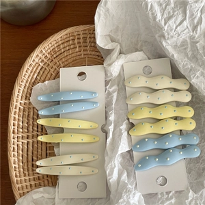 Close-up of cream candy-colored wavy polka dot hair clips set on a display card