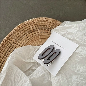 Paire de barrettes ovales en acétate marron foncé sur carte de présentation blanche