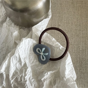 Détail d'un charme cœur bleu-gris avec nœud en cristal sur élastique marron