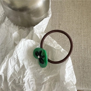 Gros plan d'un ornement vert avec noeud noir et diamant sur élastique à cheveux marron