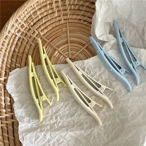 Detailed view of cream-colored wavy hair clips with blue dots on white paper base