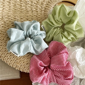 Gros plan détaillé de trois chouchous en tissu à carreaux en bleu ciel, vert et rose