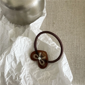 Détail d'un élastique à cheveux marron avec breloque cœur en acétate et strass étincelant