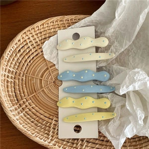 Detail of 6-piece cream hair clips set with colorful wave patterns and polka dots