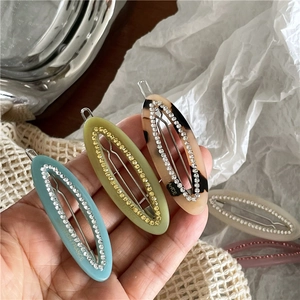 Detailed macro view of rhinestone-inlaid acetate oval hair clips in various elegant colors