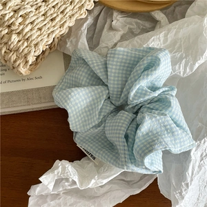 Détail du chouchou en coton à carreaux bleu clair avec étiquette de marque et plis