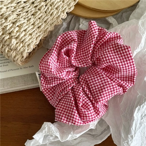 Gros plan d'un chouchou à carreaux rouges et blancs sur un fond de papier blanc esthétique