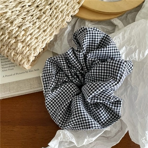 Gros plan sur un chouchou en tissu à carreaux noir et blanc à texture douce