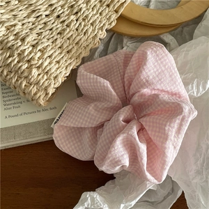 Vue détaillée du chouchou en tissu vichy rose et blanc sur un fond rustique chic