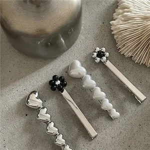 Lot de barrettes à cheveux en métal argenté avec cœurs et fleurs sur fond gris texturé