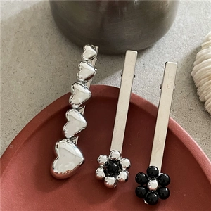 Ensemble de trois barrettes argentées avec fleurs et cœurs sur fond minimaliste
