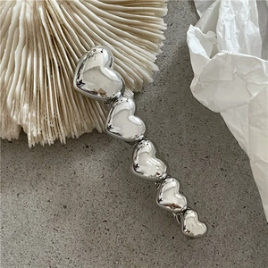 Détail d'une pince à cheveux cœur argentée avec finition métallique polie sur coquillage