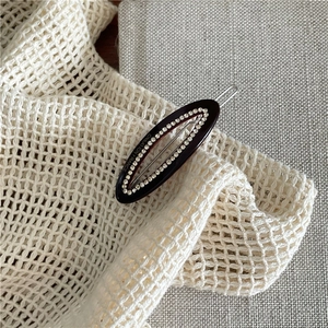 Detail of coffee-colored oval clip with micro-set rhinestones and Creation France engraving