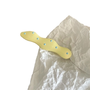 Cute cream yellow wave hair clip with blue polka dots on wrinkled white paper background