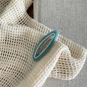 Macro detail of oval acetate hair clip with sparkling rhinestones and mint green finish