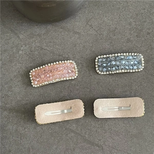 Detail view of sparkling crystal BB hair clips in pink and grey-blue with silver metal base