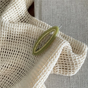Detail shot of green acetate oval hair clip with sparkling rhinestones and metal backing