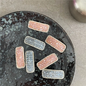 Close-up of geometric rectangular hair clips with rhinestones and pink resin crystals