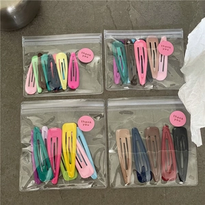 Detail view of colorful metal drip-oil drop hair clips in clear gift packaging with stickers