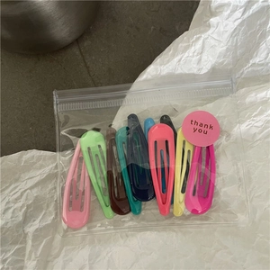 Detail of candy-colored teardrop hair clips set in a transparent zipper bag with sticker