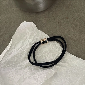 Dettaglio di elastico per capelli nero con fibbia geometrica in oro e smalto nero