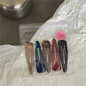 Detailed view of 5 colorful teardrop snap hair clips in a transparent pouch