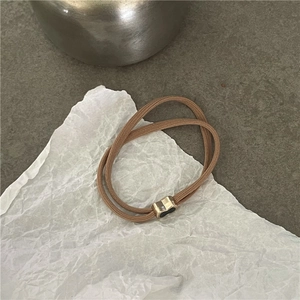 Dettaglio dell'elastico per capelli marrone con un ornamento in metallo dorato a cuore