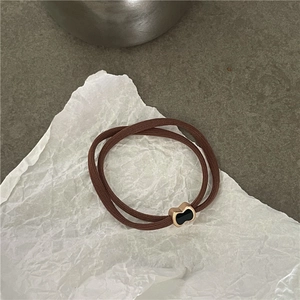 Dettaglio di elastico per capelli marrone con ciondolo a cuore d'oro su pietra