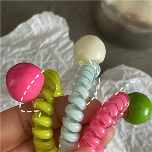 Vue rapprochée d'élastiques à cheveux spirales colorés avec de grandes perles rondes