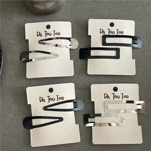 Detail view of matte black and silver metal hair clips in teardrop and rectangle shapes