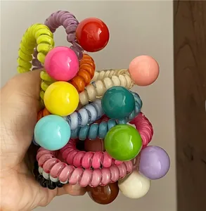 Détail d'élastiques à cheveux en spirale avec de grandes perles rondes aux couleurs vives