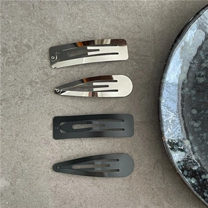 Close-up of matte black and silver metallic hair clips in rectangle and waterdrop shapes