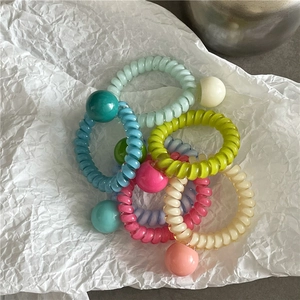 Détail d'élastiques à cheveux spirales colorés avec perles en résine sur blanc