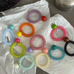Élastiques à cheveux spirales colorés avec perles rondes sur papier blanc froissé