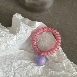 Gros plan sur l'élastique rose en cordon de téléphone avec une perle violette brillante