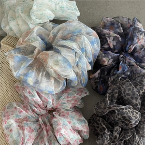 Close-up of floral print and leopard pattern mesh scrunchies on a neutral surface