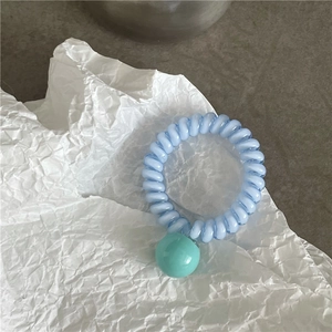 Détail de l'élastique spirale bleu clair avec une perle ronde vert menthe lisse