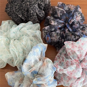 Flat lay of five assorted floral print organza scrunchies on a wooden background