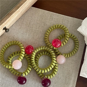 Détail d'élastiques à cheveux spirale verts avec des perles en résine colorées