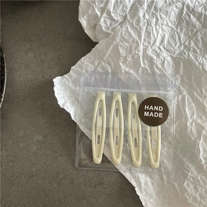 Lot de quatre barrettes ovales crème mat présentées dans un emballage de style artisanal