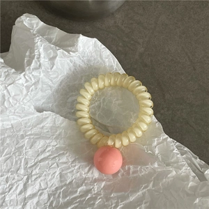 Gros plan sur l'élastique à cheveux spirale beige avec une perle décorative rose